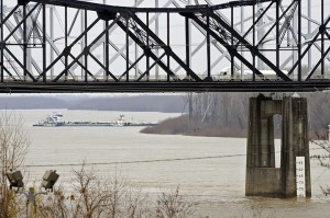 The towboat Natures Way Endeavor banks a barge against the western bank of the Mississippi River on Monday as an 18-wheeler crosses the Interstate 20 bridge. Eli Baylis | Associated Press