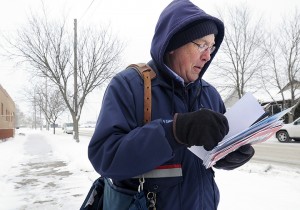Mail carrier Bruce Nicklay walks along East Third Street in Winona, Minn., delivering letters to homes Wednesday, Feb. 6, 2013. The U.S. Postal Service will stop delivering mail on Saturdays but continue to deliver packages six days a week under a plan aimed at saving about $2 billion annually, the financially struggling agency says.  Associated Press