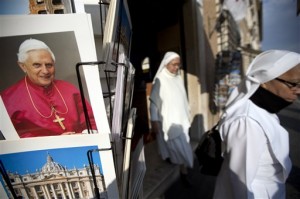 Two nuns walk past a photo of Pope Benedict XVI as they leave a souvenir shop just outside the Vatican, Tuesday, Feb. 26, 2013. Pope Benedict XVI will be known as "emeritus pope" in his retirement and will continue to wear a white cassock, the Vatican announced Tuesday, again fueling concerns about potential conflicts arising from having both a reigning and a retired pope. The pope's title and what he would wear have been a major source of speculation ever since Benedict stunned the world and announced he would resign on Thursday, the first pontiff to do so in 600 years. (AP Photo/Andrew Medichini)
