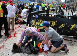 An injured woman is tended to at the finish line of the Boston Marathon,  in Boston, Monday, April 15, 2013. Two explosions shattered the euphoria of the Boston Marathon finish line on Monday, sending authorities out on the course to carry off the injured while the stragglers were rerouted away from the smoking site of the blasts. (AP Photo/The Boston Globe,  John Tlumacki) 