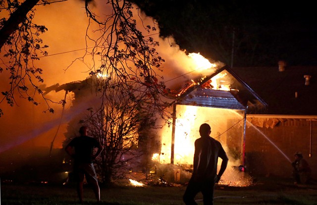 A person looks on as emergency workers fight a house fire after a near by fertilizer plant exploded Wednesday, April 17, 2013, in West, Texas. (AP Photo/ Waco Tribune Herald, Rod Aydelotte)