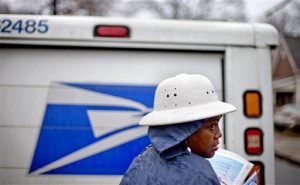 FILE - In this Feb. 7, 2013 file photo, U.S. Postal Service letter carrier Jamesa Euler, delivers mail in the rain in the Cabbagetown neighborhood, in Atlanta. The U.S. Postal Service says it will delay plans to cut Saturday mail delivery because Congress isn't allowing the change. The Postal Service said in February that it planned to cut back in August to five-day-a-week deliveries for everything except packages, as a way to hold down losses. (AP Photo/David Goldman)