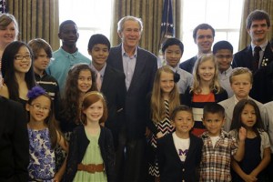Former President George W. Bush, center, poses with 43 students from Dallas-Fort Worth area schools who were the first 43 official guest to tour the Bush Presidential Library on its' opening day Wednesday, May 1, 2013, in Dallas. Bush surprised the group in the replica of the oval office. (AP Photo/Tony Gutierrez)