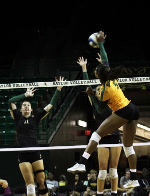 Junior middle hitter spikes the ball as freshman outside hitter Katie Staiger (right) and redshirt freshman middle hitter Sam Hill go for the block during the season opening Baylor volleyball Green vs. Gold scrimmage at the Ferrell Center on Tuesday, August 27, 2013.  Travis Taylor | Lariat Photo Editor