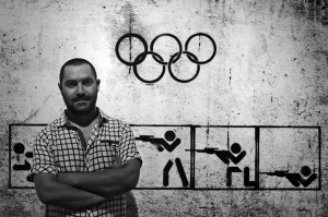 In this Monday, Sept. 16, 2013 photo, Syrian artist Tammam Azzam, 23, poses in front of one of his works, a digital print titled "Syrian Olympic" during the Young Collectors Auction at Ayyam gallery in Dubai, United Arab Emirates. The auction Monday in Dubai's evolving art district _ tucked inside an industrial zone of warehouses and businesses _ served as a window into a small but forward-looking effort to save one niche of Syria's artistic community with no end in sight to the civil war that has already claimed more than 100,000 lives.(AP Photo/Kamran Jebreili)