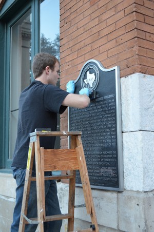 Rowlett senior Charles Stokes, member of the Dallas County Historical Commission, works to restore the plaque outside the Dallas County Administration Building, which was vandalized by conspiracy theorists. (Courtesy Photo)