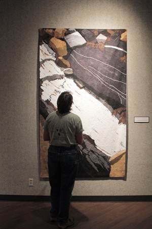 Waco resident Cindy Parongao admires an Ann Johnston quilt titled The Contact: Eureka Chimney on display in the Hooper-Schaefer Fine Arts Center on Thursday, November 7, 2013.  The quilt was made of cotton and silk and hand printed and painted with dye.      Travis Taylor | Lariat Photo Editor