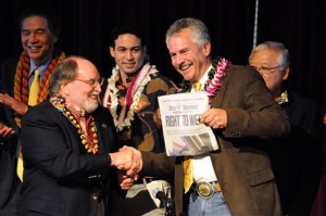 Governor Neil Abercrombie, left, and former senator Avery Chumley hold up a copy of the Star Advertiser after Abercrombie signed the bill legalizing gay marriage in Hawaii on Weds., Nov. 13, 2013 in Honolulu.  Hawaii's gay marriage debate began in 1990 when two women applied for a marriage license, leading to a court battle and a 1993 state Supreme Court decision that said their rights to equal protection were violated by not letting them marry.  Now the island chain is positioning itself for an increase in tourism as visitors arrive to take advantage of the new law, which takes effect Dec. 2. (AP Photo/Honolulu Star-Advertiser, Craig  T. Kojima)