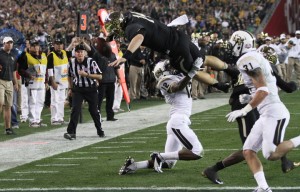 No. 14 junior quarterback Bryce Petty leaps over UCF No. 12 redshirt freshman cornerback Jacoby Glenn for a touchdown during the second quarter of the Fiesta Bowl in the University of Phoenix stadium in Glendale, Ariz. on Wednesday, Jan. 1, 2014. The Bears trail the Knights 20-28 at the half. Matt Hellman | Lariat Multimedia Producer