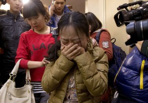 A Chinese relative of passengers aboard a missing Malaysia Airlines plane, cries as she is escorted by a woman while leaving a hotel room for relatives of passengers on March 9 in Beijing, China.