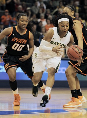 Senior guard Odyssey Sims dribbles through two Oklahoma State defenders 