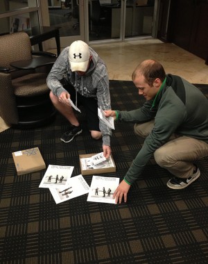 Hardin senior Luke Russell (left) and Port Neches senior Tyler Wright (right) organize posters for their client and Common Grounds artist, Drew Holcomb and the Neghbors. Russell and Wright have been spending the semester working on promoting their Friday show.