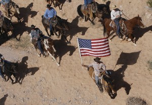 In this April 12, 2014, file photo, the Bundy family and their supporters fly the American flag as their cattle is released by the Bureau of Land Management back onto public land outside of Bunkerville, Nev. The federal Bureau of Land Management says six cattle died in the roundup of animals it says rancher Cliven Bundy allowed to graze illegally on public land outside his southern Nevada property.A Texas land dispute has outgoing Gov. Rick Perry and the Republican candidate favored to replace him, Greg Abbott, decrying the same federal agency currently embroiled in an armed standoff in Nevada. (AP Photo/Las Vegas Review-Journal, Jason Bean)