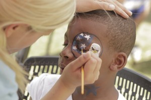 Datrayvion Frierson, 10, has an eagle and an American flag painted on his face by Wichita, Kan., sophomore Abby Reusser at the Project Come Together event hosted by Delta Epsilon Psi on Thursday on Fountain Mall.  