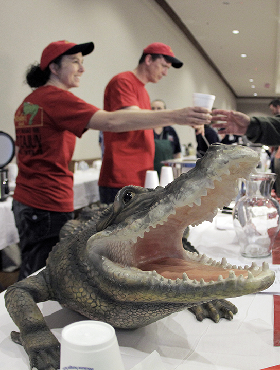 “Ally the Alligator” looks on as Angela Everett, 40, hands out a cup of shrimp gumbo from the Boudain Shack restaurant at the 2014 Feast of Caring “Soup Cook Off” event, which benefited Caritas of Waco on Tuesday  at the Waco Convention Center. 