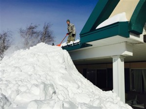 An airman with the New York Air National Guard shovels snow off a roof on Wednesday in Buffalo.Associated Press
