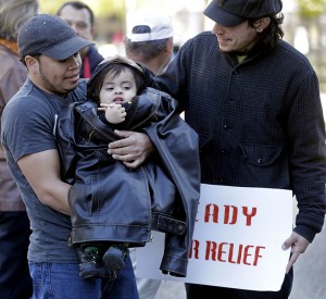 Denis Cherino of Honduras holds his 17-month old son wrapped in his coat Wednesday as immigrants and activists hold a protest outside the U.S. Citizenship & Immigration Service office in New Orleans.Associated Press
