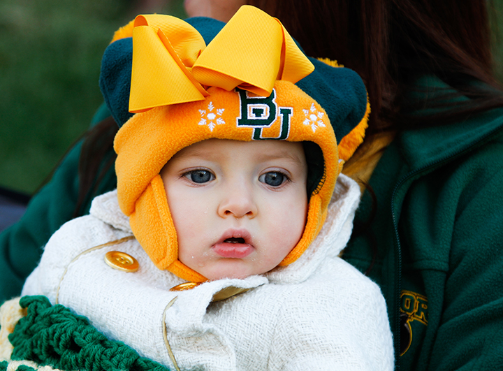 A child of a Bear fan looks on as the homecoming parade passes. Baylor's Homecoming Parade is believed to be the largest in the nation and began in 1909. Constance Atton | Lariat Photographer