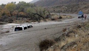 A television news crew walks away from a vehicle caught in an overnight mudslide on Soboba Road near Gilman Springs Road on Thursday in San Jacinto, Calif. Heavy rain triggered flash floods and stranded more than three dozen people in their cars in Southern California.Associated Press