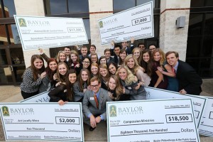 Students pose with giant checks written from Baylor University to philanthropic organizations.  