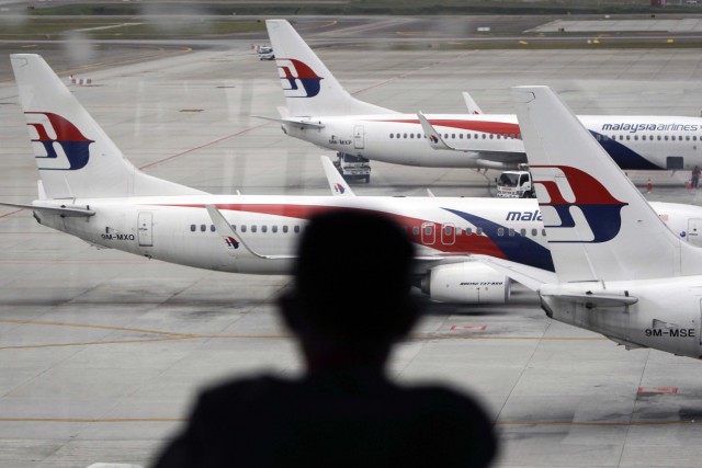 A man views a fleet of Malaysia Airline planes on the tarmac of the Kuala Lumpur International Airport, in Malaysia, Thursday, Jan. 29,  2015. Malaysia's Civil Aviation Authority officially declared the MH370 crash an accident on Thursday, fulfilling a legal obligation that will allow efforts to proceed with compensation claims. 