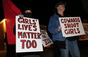 Nazzi McDonnell, left, of Colorado Springs, Colo., joins other participants in waving placards during a vigil near the scene of the early morning fatal shooting of a young woman who hit and injured a Denver Police Department officer while driving a stolen vehicle Monday, Jan. 26, 2015, in northeast Denver. (AP Photo/David Zalubowski)