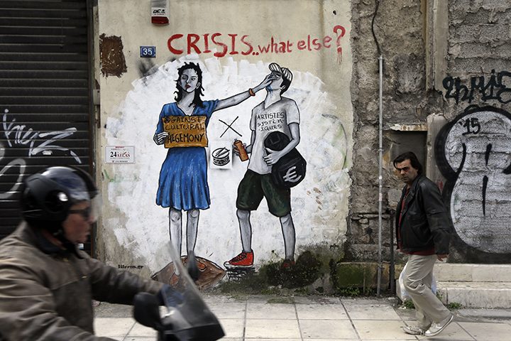 A pedestrian passes anti-austerity graffiti in Athens, Monday. Greece's radical left government and its European creditors are heading into new talks Monday on the debt-heavy country's stuttering bailout program, but expectations are low despite a fast-approaching deadline for some kind of deal. (Associated Press)
