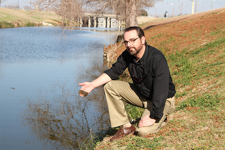 Dr. Ryan King, biology department graduate program director studies the aquatic ecosystems Tuesday in Waco Creek outside the Baylor Sciences Building.