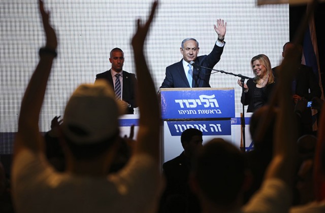 Israeli Prime Minister Benjamin Netanyahu greets supporters Tuesday at the party’s election headquarters in Tel Aviv. Exit polls from Israel’s national elections showed Prime Minister Benjamin Netanyahu’s Likud party nearly deadlocked with Isaac Herzog’s center-left Zionist Union.  Associated Press