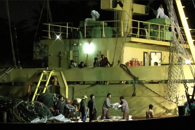 In this Nov. 27, 2014 image from video, workers from Myanmar load fish onto a Thai-flagged cargo ship in Benjina, Indonesia. An intricate web of connections separates the fish we eat from the men who catch it, and obscures a brutal truth: Your seafood may come from slaves.  Associated Press