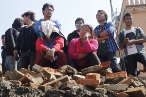 Locals watch rescue teams try to remove the body of a 12-year-old girl from a collapsed home Monday in Kathmandu, Nepal.  Associated Press