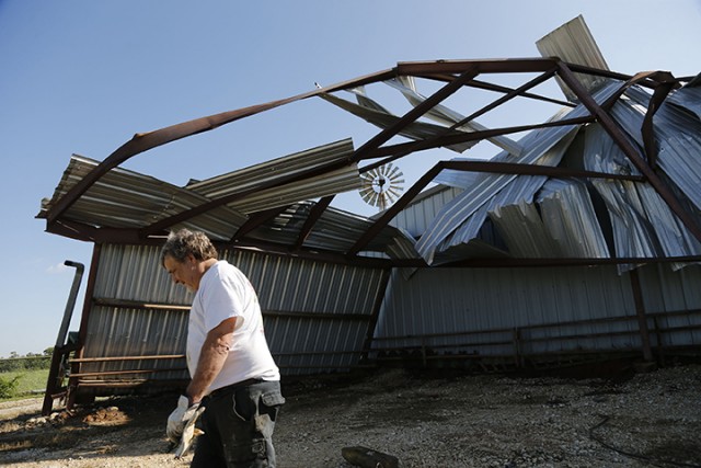 John Kuethe, owner of Green Acres Farm, surveys the damage to his barn that was partially uprooted, damaging two tractors and much of the building on Monday. Residents east of Rio Vista clean up after a severe storm system swept across parts of Texas Sunday night.  Associated Press