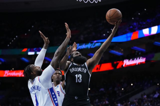 Brooklyn Nets' James Harden, right, goes up for a shot past Philadelphia 76ers' Andre Drummond during the first half of a preseason NBA basketball game, Monday, Oct. 11, 2021, in Philadelphia. (AP Photo/Matt Slocum)