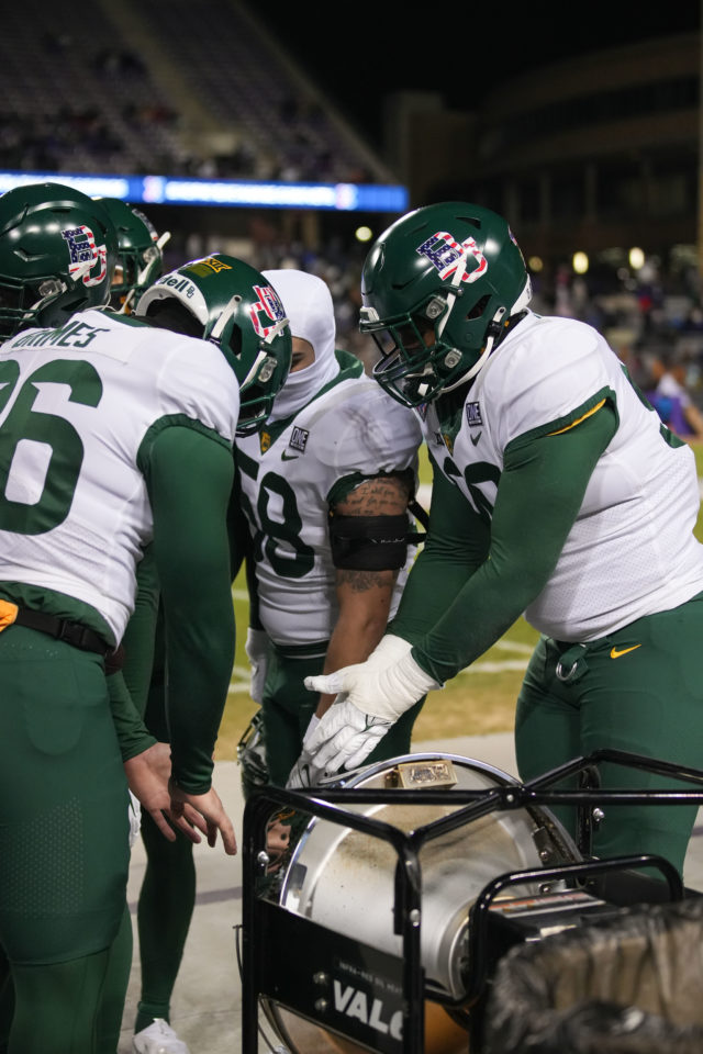 Baylor football players warm their hands on the sideline, trying to stay warm while battling below freezing temperatures during the Lockheed Martin Armed Forces Bowl on Dec. 23, 2022 at Amon G. Carter Stadium in Fort Worth. 
Josh Wilson | Roundup