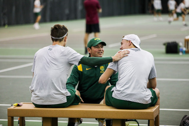 Head coach Michael Woodson (middle) checks on sophomore Ethan Muza (left) and freshman Luc Koenig (right) during doubles play of a a non-conference match against No. 9 Florida State University on Jan. 28, 2023 in the Hawkins Indoor Tennis Center. 
Kenneth Prabhakar | Photo Editor