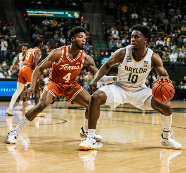 Redshirt senior guard Adam Flagler (10) uses his body to keep the Longhorn defender away during a conference game against No. 8 University of Texas, Saturday, Feb. 25, 2023, in the Ferrell Center.Kenneth Prabhakar | Photo Editor