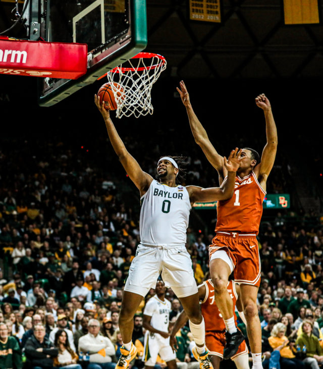 Fifth-year senior forward Flo Thamba (0) uses his right hand to finish a layup during a conference game against No. 8 University of Texas, Saturday, Feb. 25, 2023, in the Ferrell Center.Kenneth Prabhakar | Photo Editor