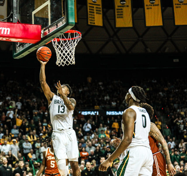 Redshirt freshman guard Langston Love (13) grabs the ball and lays it off the glass with his right hand during a conference game against No. 8 University of Texas, Saturday, Feb. 25, 2023, in the Ferrell Center.Kenneth Prabhakar | Photo Editor