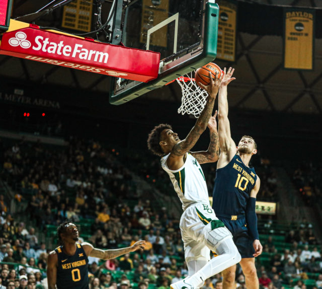 Junior forward Jalen Bridges (11) tries to finish a reverse layup under the basket during a conference game against West Virginia University, on Feb. 13, 2023, in the Ferrell Center.Kenneth Prabhakar | Photo Editor