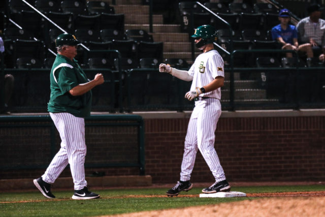 Head coach Mitch Thompson, left, congratulates one of his players, right, for reaching third base during the third inning of a non-conference midweek game against Houston Christian University, Tuesday, Feb. 21, 2023, at Baylor Ballpark.
Assoah Ndomo | Photographer