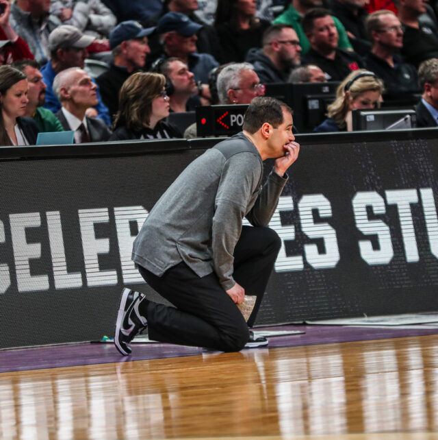 Head coach Scott Drew kneels near the scorer’s table dribbles the ball near the logo during No. 3 seed Baylor men’s basketball’s opening round game of the NCAA Tournament versus No. 14 seed University of California, Santa Barbara, on March 17, in the Ball Arena in Denver. 
Kenneth Prabhakar | Photo Editor