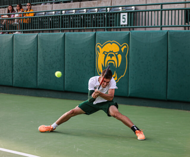 Sophomore Ethan Muza nearly does the splits as he returns the ball with both hands on the racket during Baylor men's tennis' Saturday doubleheader against the University of Texas Rio Grande Valley and Texas Tech University, on April 1, at the Hurd Tennis Center. Kenneth Prabhakar | Photo Editor