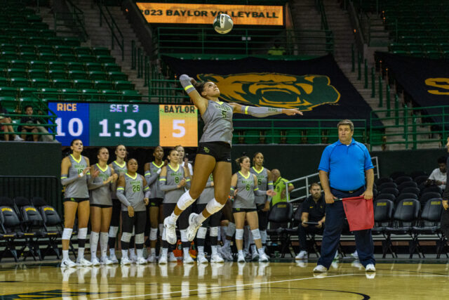 Freshman outside hitter Kyndal Stowers leaps and hits a service during No. 16 Baylor volleyball's home opener against No. 18 Rice University on Friday in the Ferrell Center. Lilly Yablon | Photographer