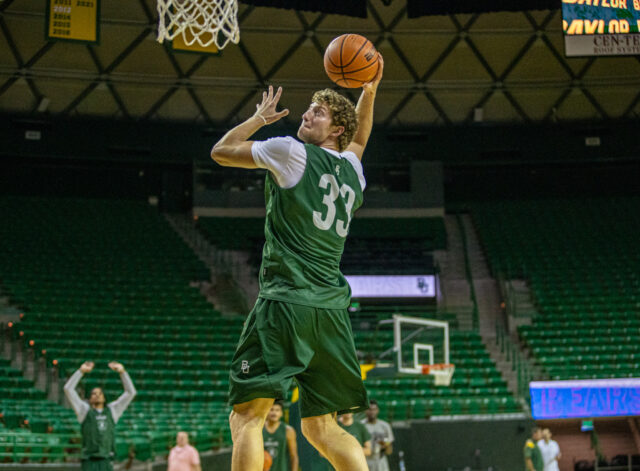 Senior forward Caleb Lohner (33) punches in a 180-degree dunk during Baylor men's basketball's first practice of the fall on Tuesday in the Ferrell Center. Lilly Yablon | Photographer
