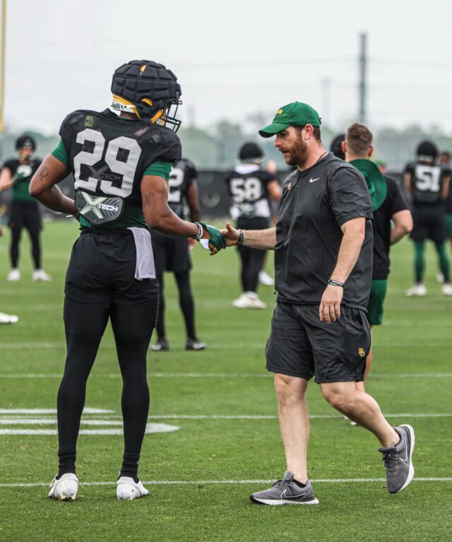Defensive coordinator and safeties coach Matt Powledge (right) shows some love to redshirt sophomore Romario Noel (29, left) during Baylor football's sixth day of spring practice on April 4 at the squad's outdoor football practice field. Kenneth Prabhakar | Photo Editor