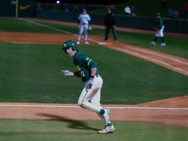 Redshirt sophomore first basemen Jack Little smiles at the dugout after drawing a walk and running the wrong direction in the