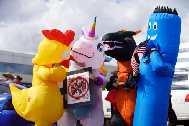 Demonstrators wearing inflatable costumes pose for a photo at the No Kings Protest on Saturday morning at Freedom Drive in