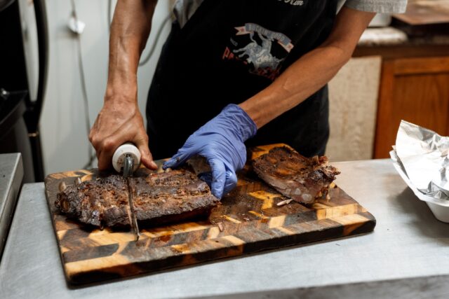 Hicks slices smoked ribs fresh off the pit at Papa Jack’s BBQ. The family-run restaurant has become a local favorite for its hearty portions and hospitality. Courtesy of Reece Reiling.