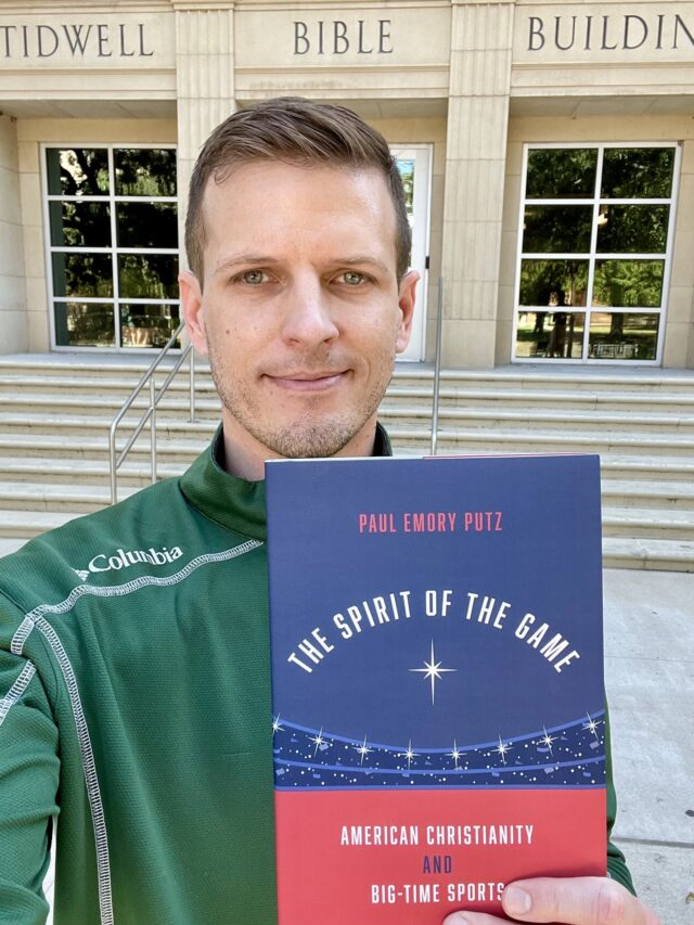 Dr. Paul Emory Putz poses in front of Tidwell with his first published book, "The Spirit of the Game; American Christianity and Big-Time Sports." Photo courtesy of Paul Emory Putz