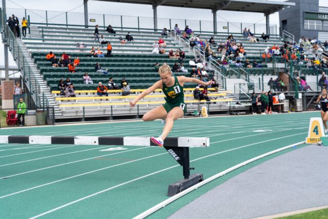 Freshman distance runner Evanna Jacobsen jumps over hurdles during the steeple chase event at the Clyde Hart Track and Field Stadium on Saturday morning. Caleb Garcia | Photographer